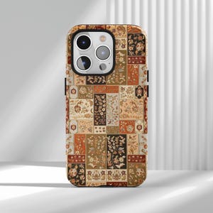 May include: A phone case with a patchwork design featuring floral and geometric patterns in shades of brown, beige, orange, and black. The case has a black border and a camera cutout.
