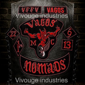 Op de afbeelding: Een zwart leren vest met rode geborduurde patches en tekst. De achterkant toont de tekst VFFV, VAGOS, VAGOS MC, NOMADS, 22, 6, 13 en 1%. Een centraal rood grafisch ontwerp toont een gehoornde figuur op een motorfiets. Het vest heeft vetersluitingen aan de zijkanten.