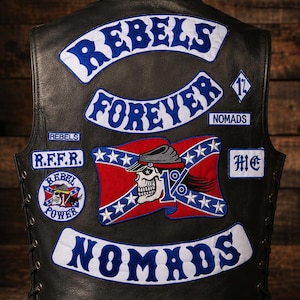 Könnte beinhalten: Schwarze Lederweste mit mehreren aufgestickten Aufnähern. Auf den Aufnähern stehen die Worte "REBELS FOREVER NOMADS" in Blau und Weiß, ein Totenkopf auf einer rot-blauen Flagge sowie die Buchstaben "R.F.F.R." und "MC".