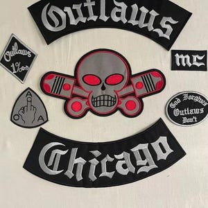 May include: A collection of embroidered patches with a biker theme. The patches feature the word "Outlaws" in a gothic font, a skull with red eyes and pistons, and the word "Chicago". Other patches include the text "1%" and "God Forgives Outlaws Don't".
