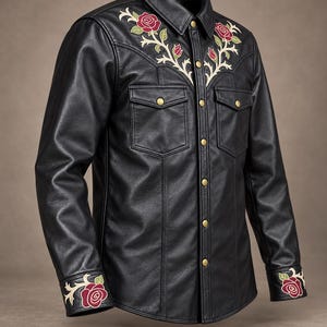 May include: A black leather shirt featuring embroidered red roses with green leaves on the chest yoke and cuffs. The shirt has a pointed collar, two chest pockets with flaps, and gold-toned metal snap buttons down the front placket.