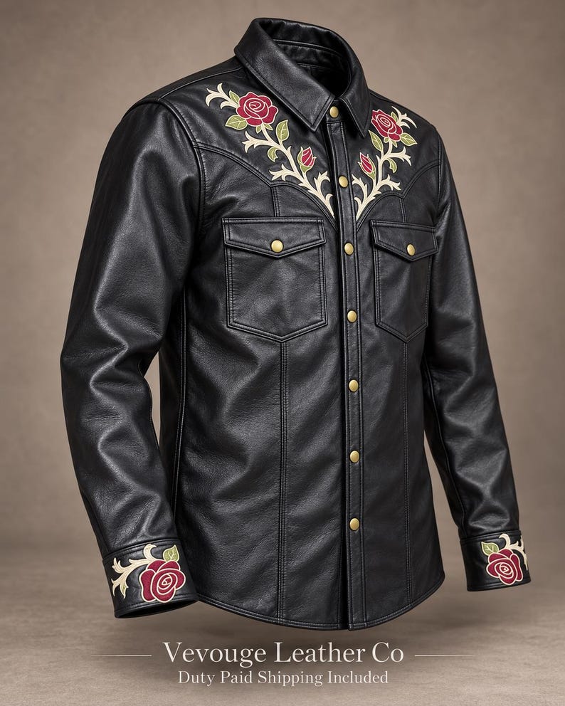 May include: A black leather shirt featuring embroidered red roses with green leaves on the chest yoke and cuffs. The shirt has a pointed collar, two chest pockets with flaps, and gold-toned metal snap buttons down the front placket.