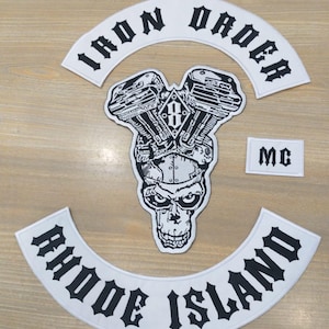 May include: A set of white embroidered patches with black text and designs. The patches include a curved "IRON ORDER" patch, a skull and engine design, a small "MC" patch, and a curved "RHODE ISLAND" patch.