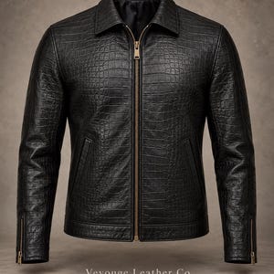 Puede incluir: Una chaqueta negra con un patrón texturizado de piel de cocodrilo, con cuello en punta, una cremallera metálica dorada de longitud completa y dos bolsillos laterales. Las mangas tienen puños con cremallera dorada. Texto Vevouge Leather Co.