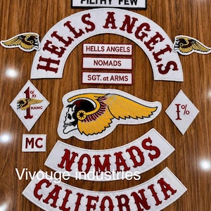 Könnte beinhalten: Eine Sammlung bestickter Aufnäher mit dem Text HELLS ANGELS, NOMADS, SGT. at ARMS, FILTHY FEW, MC und CALIFORNIA in Rot auf weißem Stoff. Enthält Totenkopf- und Flügel-Embleme, rautenförmige 1%-Aufnäher und geschwungene Rocker-Aufnäher.