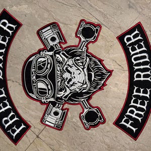 Può includere: Set di toppe ricamate per motociclisti con un design centrale con teschio, occhiali e pistoni, circondato dalle parole "FREE BIKER" e "FREE RIDER" in lettere bianche su toppe nere arcuate con bordi rossi. Per giacche o gilet.