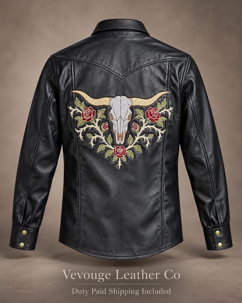 May include: A black leather jacket featuring a large embroidered design on the back. The embroidery depicts a white longhorn skull surrounded by red roses and green vines. The jacket has a collar, long sleeves with gold-tone buttons, and a yoke.