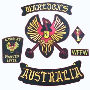 Puede incluir: Un conjunto de parches bordados con los textos "WARLOCKS" y "AUSTRALIA". El parche central presenta un águila estilizada con detalles rojos y amarillos. Otros parches incluyen "FOREVER LIFER" y "WFFW".
