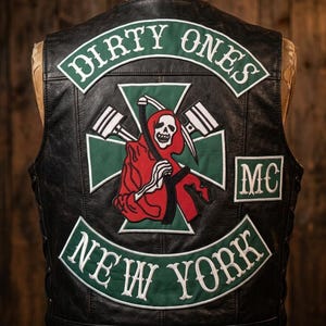 May include: Black leather vest with patches. The patches display the words "DIRTY ONES" and "NEW YORK" in white lettering on green backgrounds. A central patch shows a Grim Reaper figure in red, holding a scythe.