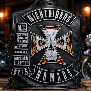 Puede incluir: Chaleco de cuero negro con parches bordados. Los parches incluyen las palabras "NIGHTRIDERS" y "NOMADS", junto con un diseño de calavera y cruz. Parches adicionales muestran "M.C.", "ONE FOR ALL", "SET AT ARMS", "ENFORCER", "MOTHER CHAPTER" y "UFFN".