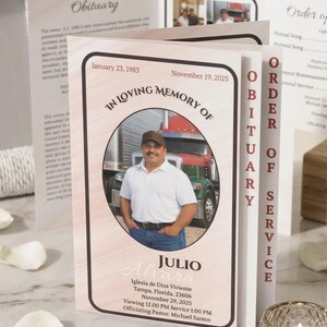 May include: A memorial service program with a photo of a man in a white shirt and a truck in the background. The program includes the text "In Loving Memory Of" and the name "Julio Alvara". The program also includes the dates January 23, 1983 and November 19, 2025.