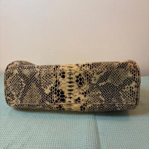 Peut inclure: Un sac &agrave; main rectangulaire avec un motif peau de serpent dans les tons beige, noir et cr&egrave;me. Le design du sac imite la texture et la coloration des &eacute;cailles de serpent, offrant un accessoire unique et &eacute;l&eacute;gant.