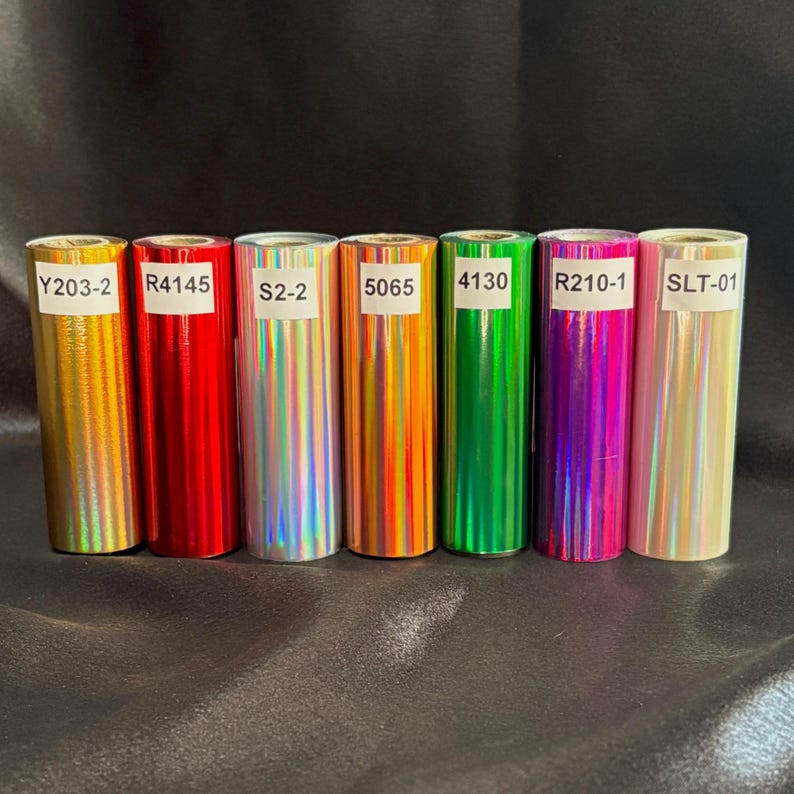May include: Seven rolls of colorful, metallic foil paper. The rolls are labeled with codes: Y203-2, R4145, S2-2, 5065, 4130, R210-1, and SLT-01. The colors include gold, red, silver, orange, green, purple, and pink.