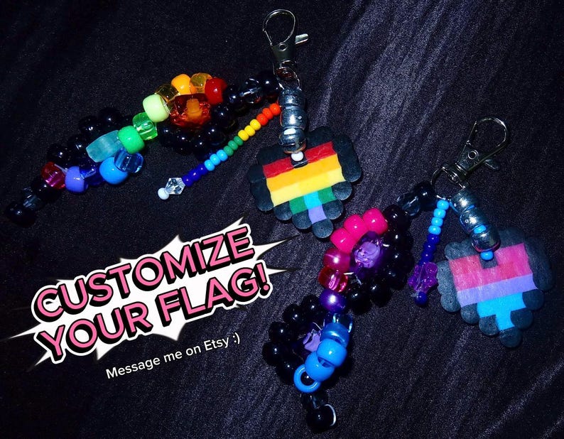 May include: Two keychains featuring black plastic beads, colorful pony beads, and pixelated heart charms attached to silver-tone lobster clasps. The text CUSTOMIZE YOUR FLAG! is displayed in white and pink lettering over a white speech bubble graphic.