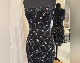 Elegante conjunto de top y falda bordados a mano con flores negras.