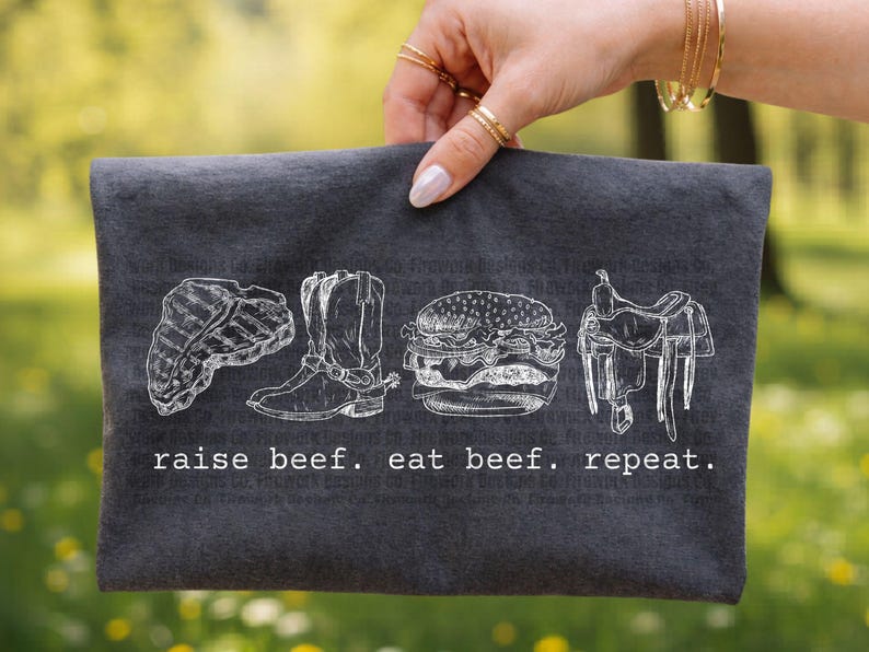 May include: Dark gray fabric pouch with a white illustration of a steak, cowboy boot, burger, and saddle. The text "raise beef. eat beef. repeat." is printed below the illustrations. The pouch is held by a person.