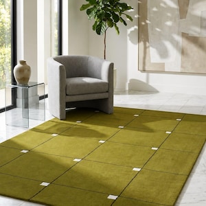 May include: A rectangular area rug featuring a solid olive green surface divided into a grid pattern by thin black lines, with small white square accents positioned at the intersections of the grid lines across the entire floor covering.