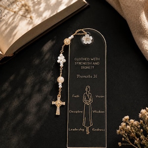 Peut inclure: Un marque-page rectangulaire en acrylique noir avec un texte doré indiquant Clothed with strength and dignity, Proverbs 31, et un dessin au trait d'une personne entouré des mots Faith, Vision, Discipline, Wisdom, Leadership et Kindness.