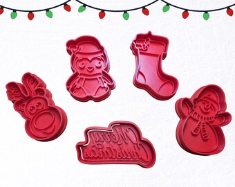 May include: Red Christmas-themed cookie cutters in various shapes: a reindeer, penguin, stocking, snowman, and a "Merry Christmas" text. Festive holiday baking tools for creating seasonal treats.