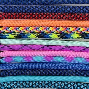 May include: Close-up of a collection of colorful shoelaces. The laces are in various colors, including blue, red, orange, yellow, green, purple, and pink. Each lace has a metal aglet at the end. The laces have different patterns.