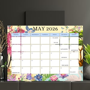 Puede incluir: Un calendario decorativo de mayo de 2026 con un diseño floral y de pájaros. El calendario presenta un fondo amarillo claro con flores rosas, pájaros azules y un cisne. Incluye fechas, festivos y fases lunares.