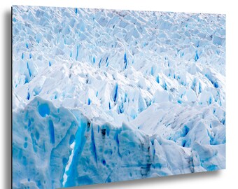 May include: A close-up photograph of a glacier, showcasing a vast expanse of ice formations. The image highlights the textured surface of the ice, with shades of white and blue. The glacier's surface is marked by deep crevasses and ridges.