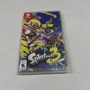 May include: Splatoon 3 video game case for the Nintendo Switch. The cover art features a yellow-haired character with a weapon, set against a blue and yellow background. The game title "Splatoon 3" is prominently displayed.