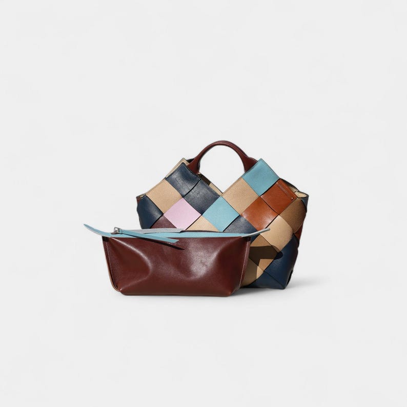 May include: A woven leather tote bag with a matching pouch. The tote features a patchwork design in shades of tan, navy, pink, and blue. The pouch is a deep brown with a light blue accent.