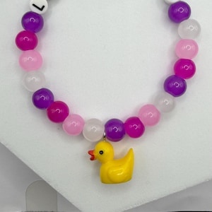 Beaded bracelet with purple and pink stones, white letter beads spelling LUCKY DUCK, and a yellow rubber duck charm.