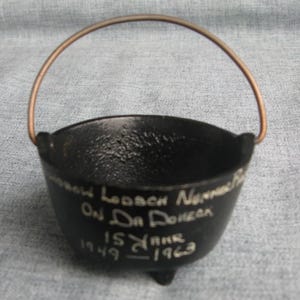 May include: A small, black cast iron cauldron with a copper handle. The cauldron has three small feet and white text that reads "Morrow Lodge No. On Da Donee 15 Yrs 1949-1963".