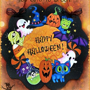 May include: A Halloween-themed wooden sign with the text "Too Cute to Spook!" and "Happy Halloween!". The sign features cartoon illustrations of a ghost, pumpkin, cat, bat, and Frankenstein's monster. The sign is painted in bright colors.