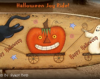 Op de afbeelding: Een handgeschilderd houten bord met een Halloween-thema. Het bord toont een zwarte kat, een pompoen en een spook dat op een kar rijdt. De tekst op het bord luidt "Halloween Joy Ride!" en "Happy Halloween".