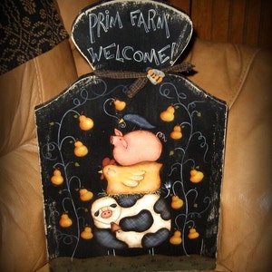 May include: Black wooden sign with the text "Prim Farm Welcome!" painted in white. The sign features a whimsical illustration of a pig, a chicken, and a cow with black and white spots, surrounded by pear branches with yellow pears.