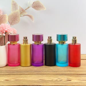 Peut inclure: Six flacons de parfum cylindriques en verre avec des embouts vaporisateurs métalliques et des bouchons assortis. Les flacons sont de couleur rose translucide, or opaque, violet translucide, noir mat, bleu translucide et rouge translucide.