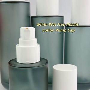 May include: Several grey frosted glass bottles with white lotion pump caps are shown. The text "White BPA Free Plastic Lotion Pump Cap" is visible. The bottles are cylindrical and have a modern design, suitable for lotions.