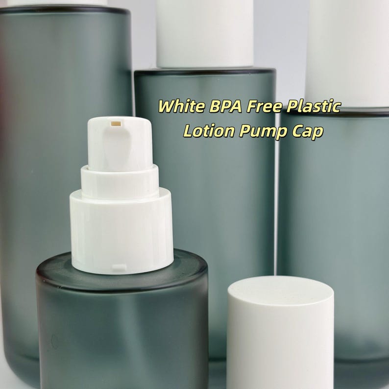 May include: Several grey frosted glass bottles with white lotion pump caps are shown. The text "White BPA Free Plastic Lotion Pump Cap" is visible. The bottles are cylindrical and have a modern design, suitable for lotions.