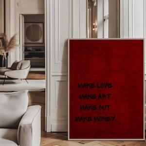 Może przedstawiać: Oprawiony czerwony wydruk artystyczny ze słowami "MAKE LOVE, MAKE ART, MAKE OUT, MAKE MONEY" w czarnych literach. Grafika ma teksturowany wygląd i jest prezentowana we współczesnym wnętrzu.