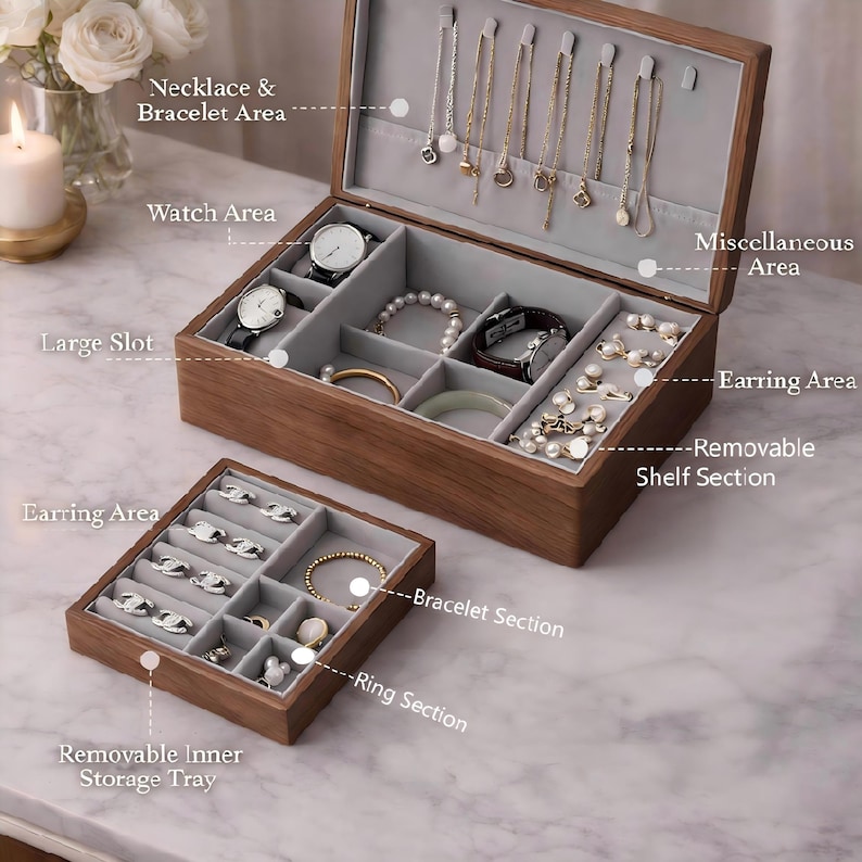 Op de afbeelding: Een houten sieradendoos met meerdere compartimenten voor kettingen, armbanden, oorbellen en horloges. De doos is open en toont diverse sieraden. Een kleinere, uitneembare lade is ook zichtbaar.