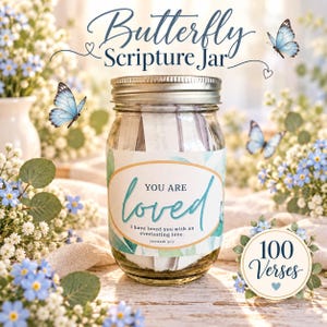 Pode incluir: Um frasco de vidro com tampa prateada contendo tiras de papel, com um rótulo que diz Butterfly Scripture Jar, You are loved, I have loved you with an everlasting love. Jeremiah 31:3, e um emblema circular com 100 Verses.