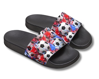 May include: A pair of black slide sandals with a soccer ball design. The top of each sandal features a pattern of soccer balls, red and blue paint splatters. The sandals are designed for casual wear.