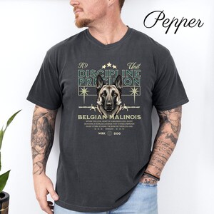 May include: Dark gray t-shirt featuring a Belgian Malinois dog graphic. The design includes the text "K9 Unit Discipline Precision" and "Belgian Malinois". The shirt has a V-neck and short sleeves.