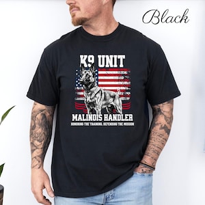 Peut inclure: T-shirt noir avec une illustration de chien Malinois, le texte "K9 UNIT MALINOIS HANDLER" et un motif de drapeau américain. Le t-shirt comprend également le texte "HONORING THE TRAINING, DEFENDING THE MISSION."