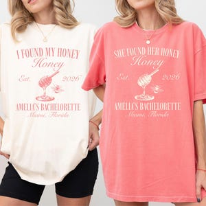 May include: Two oversized t-shirts, one ivory and one watermelon, feature a pink graphic. The ivory shirt reads "I FOUND MY HONEY" with a honey dipper and bee illustration, "Est. 2026," and "AMELIA'S BACHELORETTE Miami, Florida." The watermelon shirt says "SHE FOUND HER HONEY" with the same design.