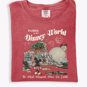 Puede incluir: Camiseta roja con un dise&ntilde;o de Disney World en Florida. El dise&ntilde;o incluye a Mickey Mouse, un castillo, Spaceship Earth y el texto "Florida Disney World" y "The Most Magical Place On Earth."