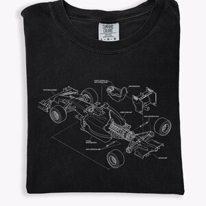 May include: Black t-shirt featuring a white schematic diagram of a race car. The diagram includes labels for various components like the front wing assembly, suspension arms, and cockpit. The shirt has a Comfort Colors tag.