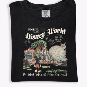 Puede incluir: Camiseta negra con un dise&ntilde;o gr&aacute;fico de Disney World en Florida. El dise&ntilde;o incluye el texto "Florida Disney World Est. 1971" y "The Most Magical Place On Earth". El gr&aacute;fico muestra a Mickey Mouse, un castillo y otros iconos del parque.
