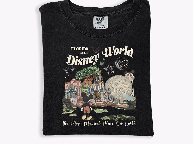 Puede incluir: Camiseta negra con un dise&ntilde;o gr&aacute;fico de Disney World en Florida. El dise&ntilde;o incluye el texto "Florida Disney World Est. 1971" y "The Most Magical Place On Earth". El gr&aacute;fico muestra a Mickey Mouse, un castillo y otros iconos del parque.