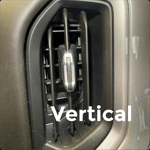 May include: Close-up of a car's air vent with vertical slats. A silver-colored, rectangular object is centered within the vent. The word "Vertical" is written in white, bold text at the bottom of the image.