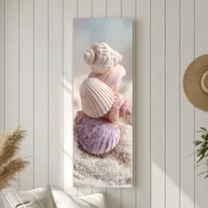 May include: A vertical canvas print featuring a stack of seashells in shades of white, pink, and purple, resting on white sand. The shells are arranged against a soft, blurred background, evoking a beach theme.