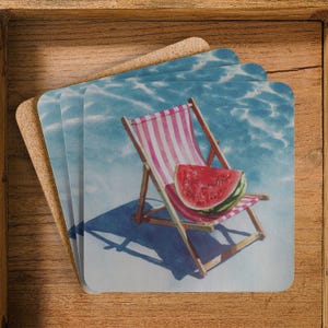 May include: Set of four square coasters with a watercolour design. Each coaster shows a beach chair with pink and white stripes, a watermelon slice, and a blue water background. The coasters are made of a cork material.